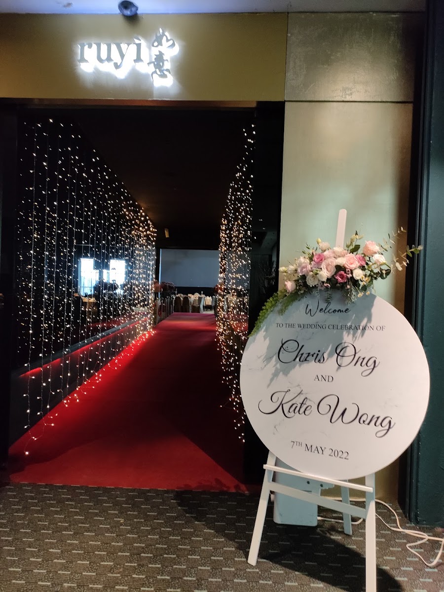 A wedding welcome board with floral arrangement at a restaurant entrance